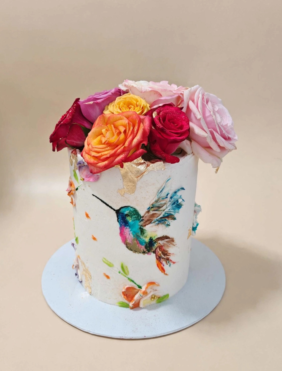 White cake with hummingbird painting and rose crown