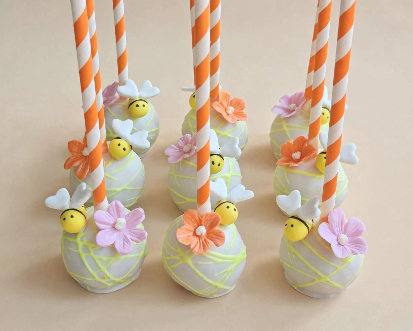 Bee and blossom cake pops on striped paper straws