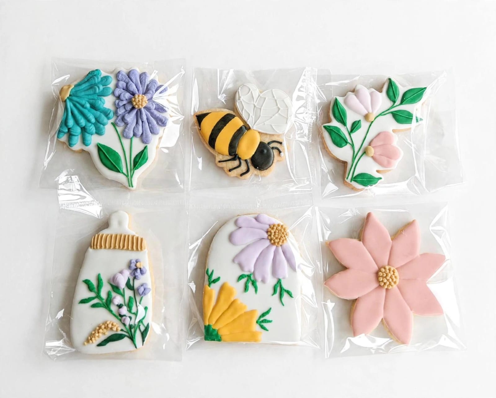 Individually wrapped iced cookies with flowers, a bee and a baby bottle