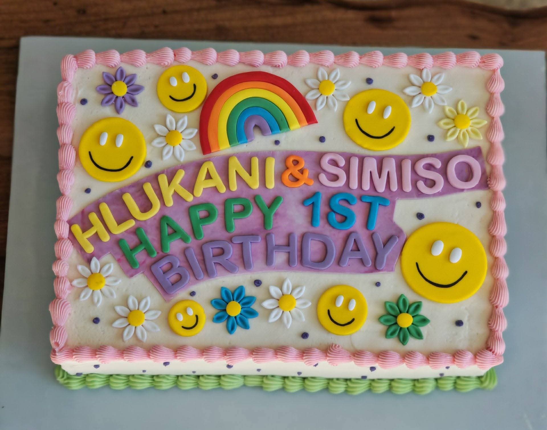 First birthday sheet cake with a fondant rainbow, smiley faces and daisies