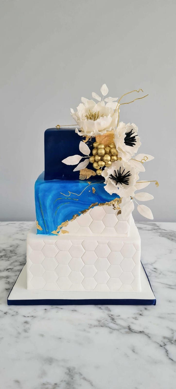 Navy and white cake with gold leaf and dried florals
